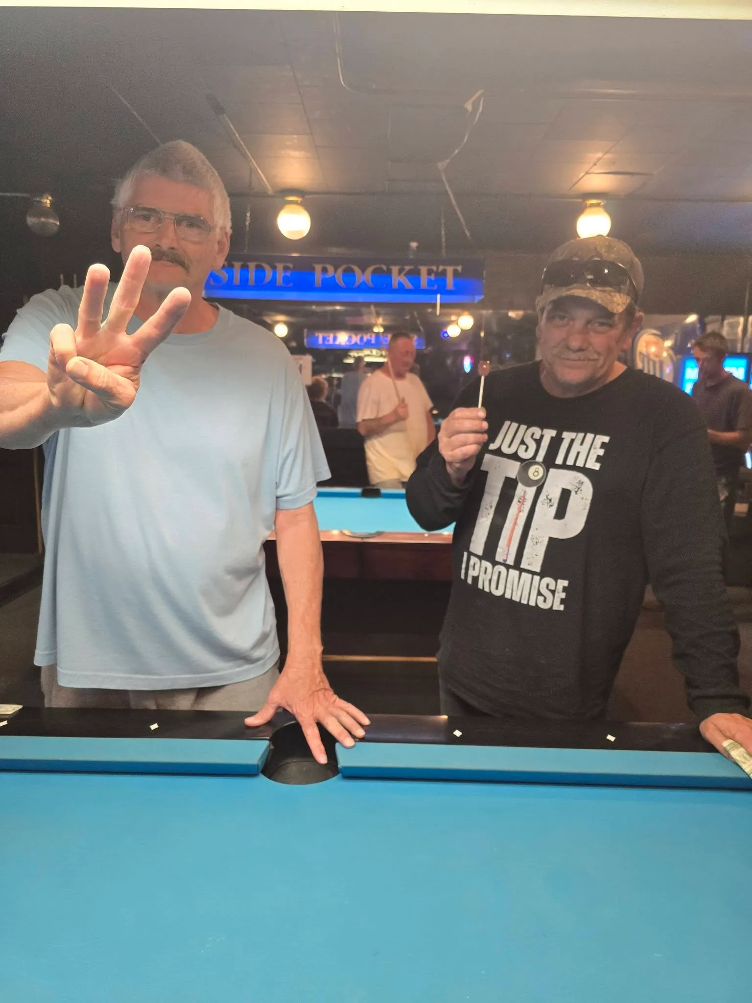 Two tournament winners posing at the table with their prize