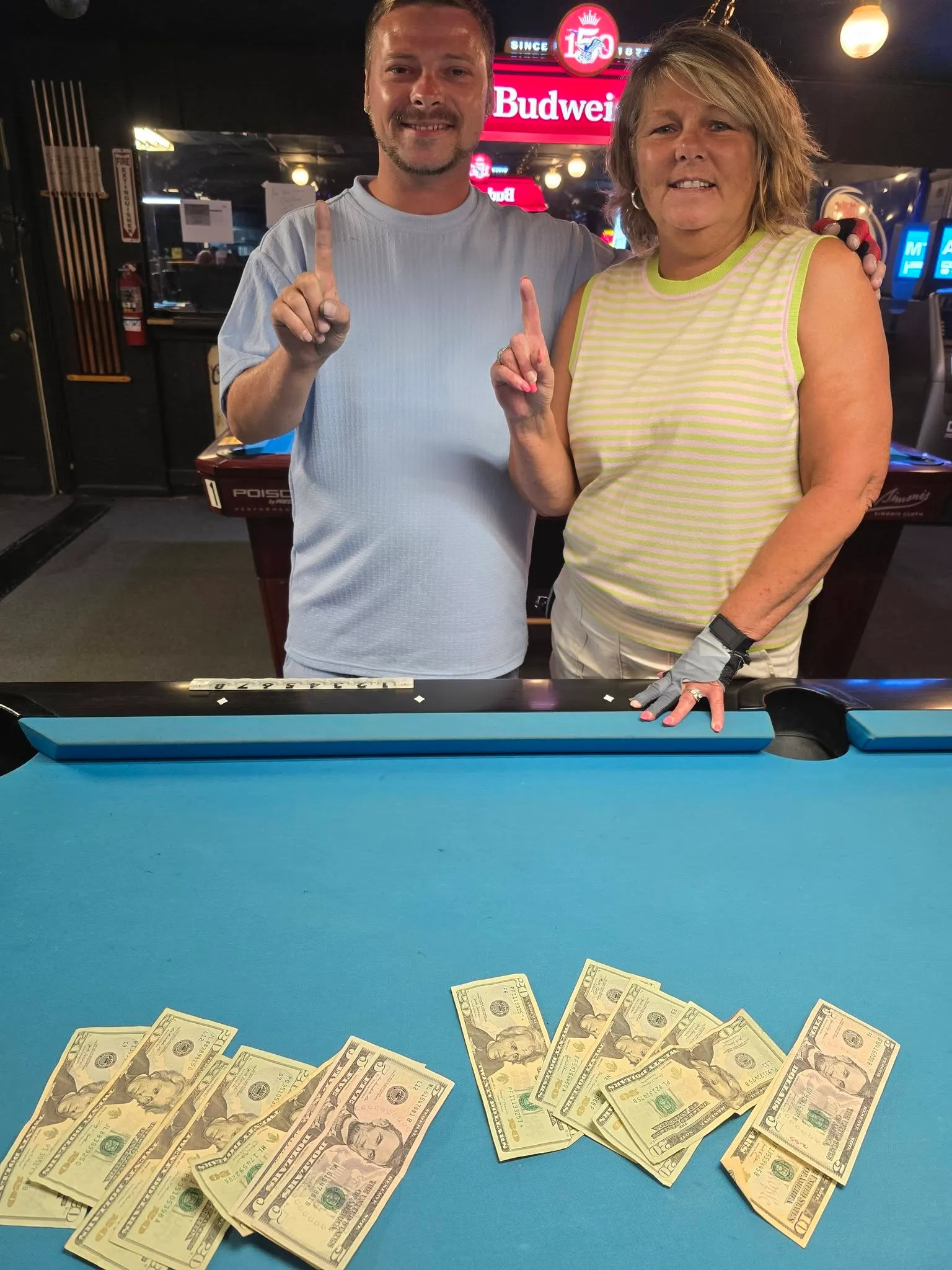 Two smiling winners with their cash spread on the felt
